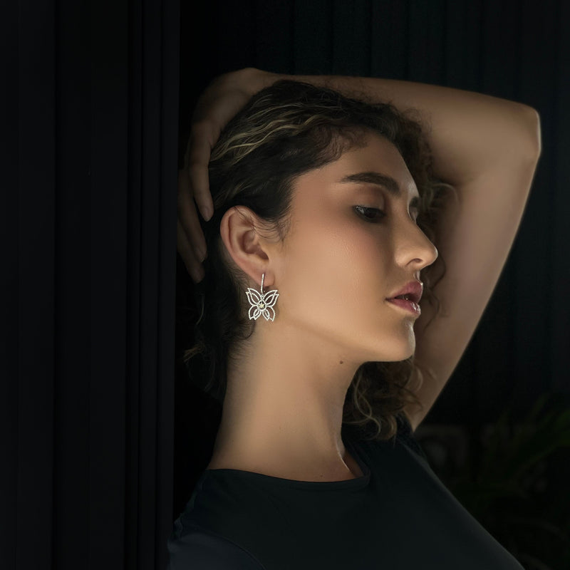 Veilari Model wearing butterfly earrings against a dark background.