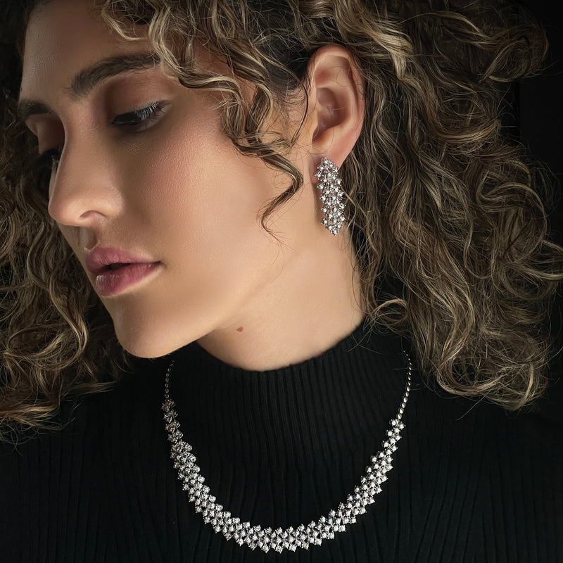 veilari model wearing a necklace and earrings against a dark background