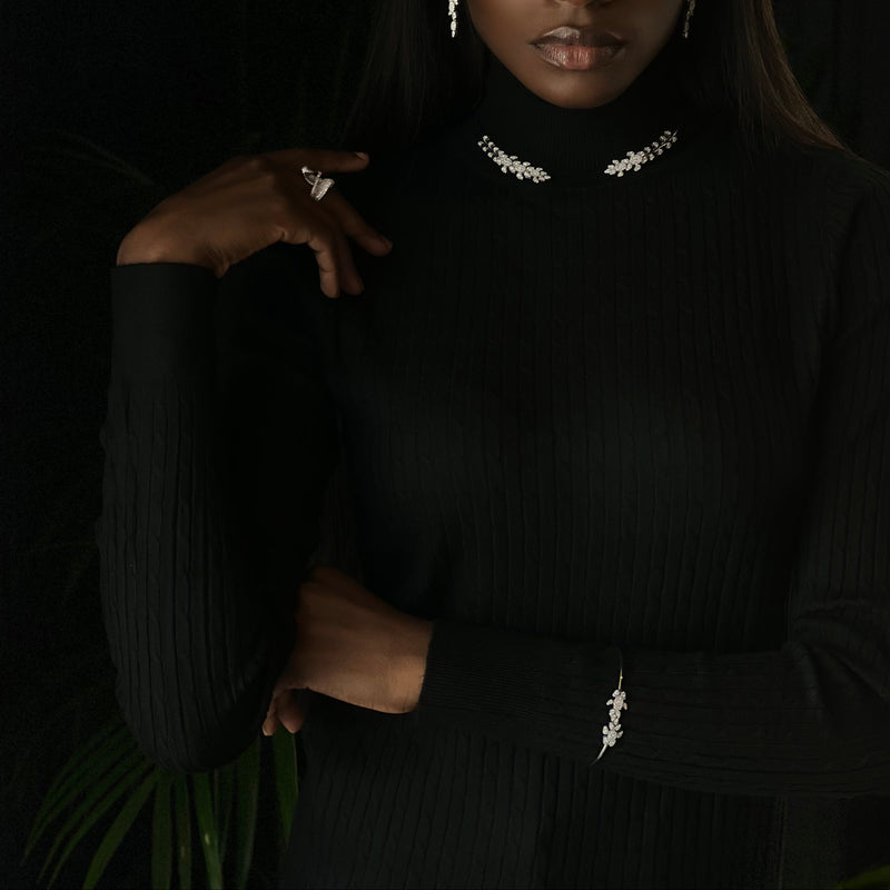 Veilari Model wearing a black turtleneck with floral details jewellery against a dark background