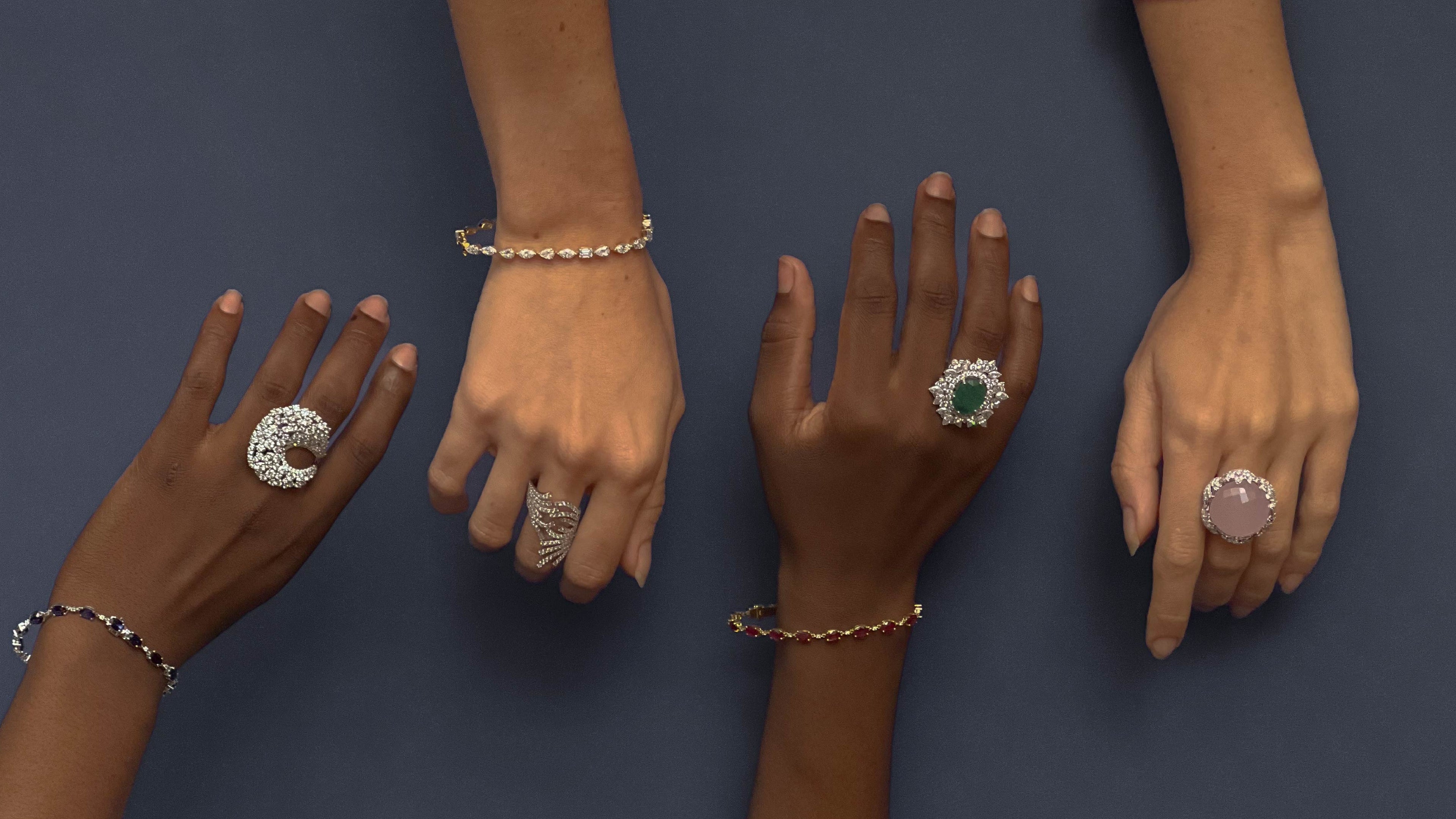 Hands with various rings and bracelets on a dark background